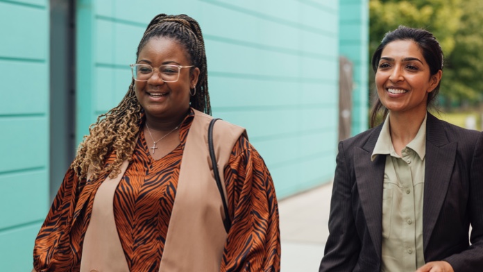 Two cheerful women walking on a sidewalk