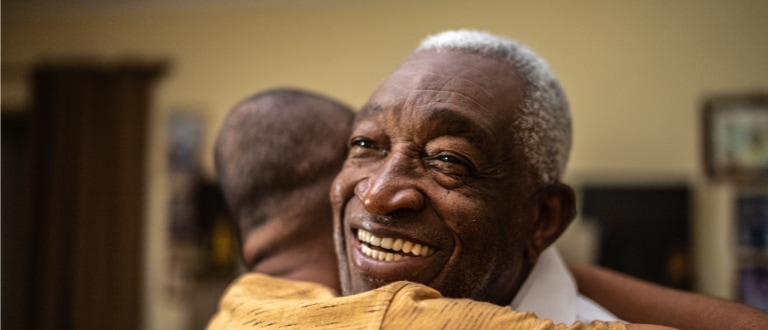 Caregiver hugging senior man at home