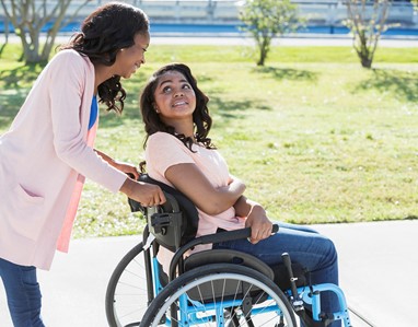 A woman pushes a teenage girl's wheelchair.