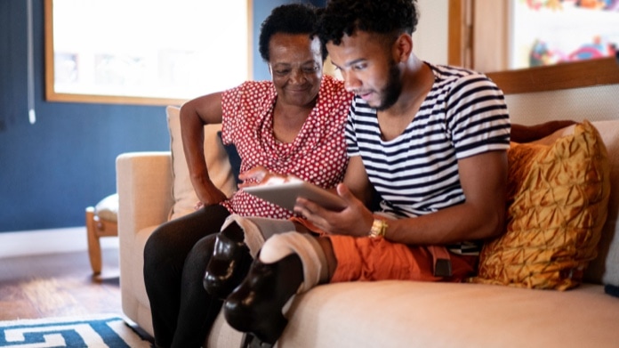 Young man with disability using digital tablet with his caretaker