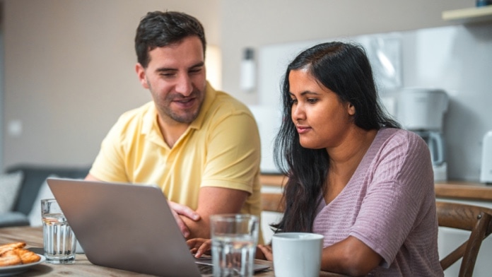 Man and woman chatting while looking at a laptop