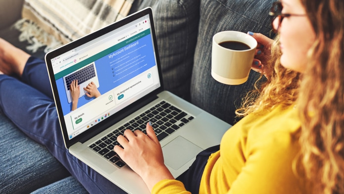 Young woman using a laptop and having coffee on the sofa at home