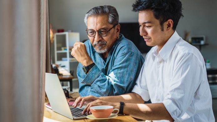 Young caregiver and senior person using a laptop at home