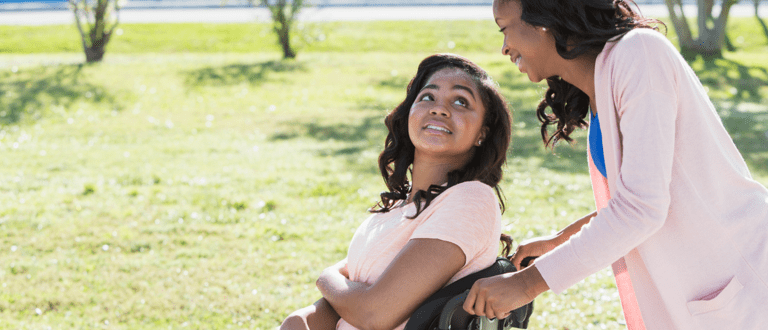 A woman pushes a teenage girl's wheelchair.