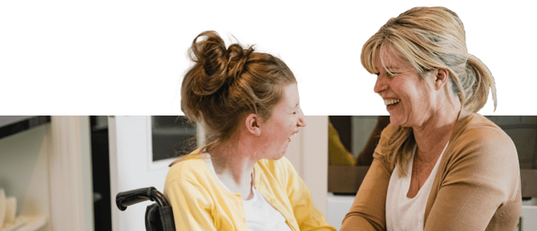 Caregiver and girl on a wheelchair smiling