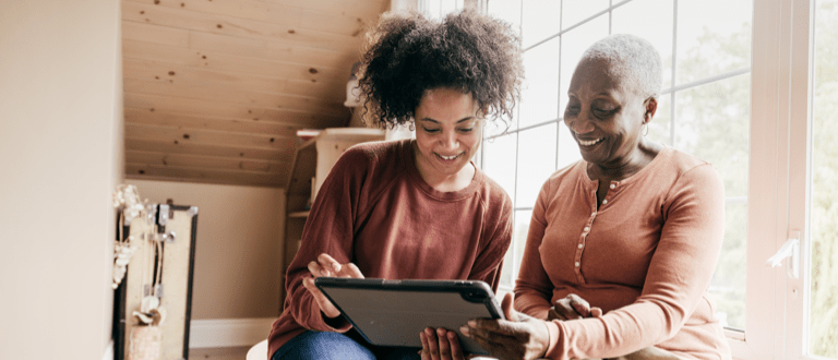 Young woman helps an elderly woman to use a tablet